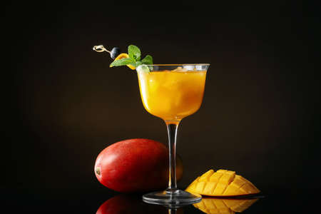 Glass of tasty mango margarita on dark backgroundの写真素材