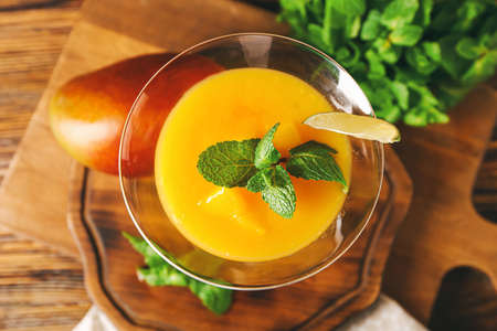 Glass of tasty mango margarita and ingredients on wooden background, closeupの写真素材