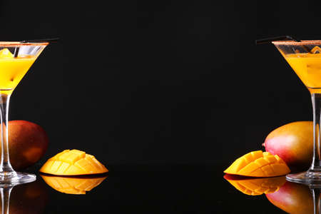 Glasses of tasty mango margarita on dark backgroundの写真素材
