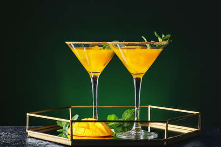 Tray with tasty mango margarita and mint on dark color backgroundの写真素材