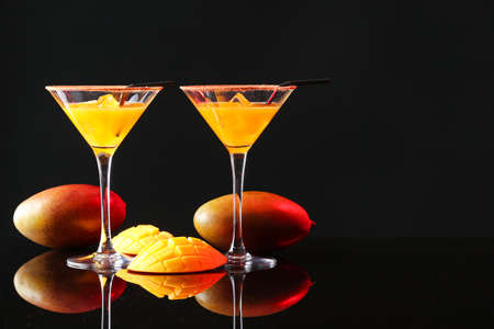Glasses of tasty mango margarita on dark backgroundの写真素材