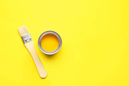 Can of yellow paint and brush on color backgroundの写真素材