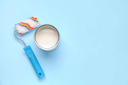 Can of white paint and roller on color backgroundの写真素材