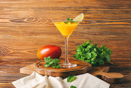 Glass of tasty mango margarita and ingredients on wooden backgroundの写真素材