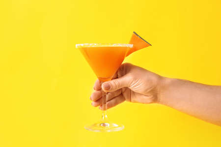 Female hand with glass of tasty pumpkin pie martini on color backgroundの写真素材