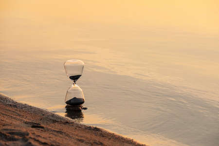 Stylish hourglass near river at sunsetの写真素材