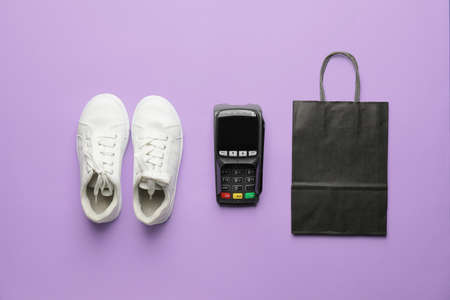 Payment terminal with pair of sneakers and paper bag on color backgroundの写真素材