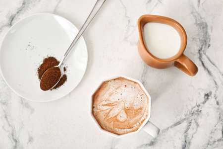 Composition with cup of tasty latte, coffee powder and pitcher with milk on light backgroundの写真素材