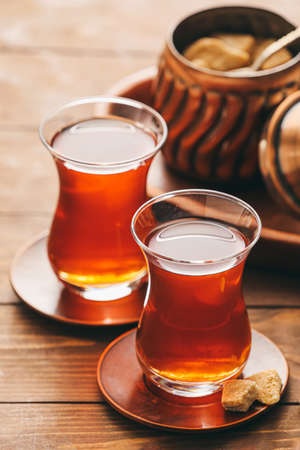 Glasses of tasty Turkish tea and bowl with sugar on wooden backgroundの写真素材