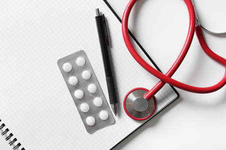 Modern stethoscope, notebook, pills and pen on light background, closeupの写真素材