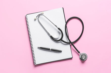 Modern stethoscope, notebook and pen on color backgroundの写真素材
