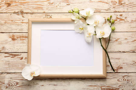 Beautiful orchid flowers and blank frame on wooden backgroundの写真素材