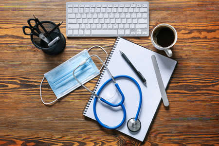 Composition with modern stethoscope and computer keyboard on wooden backgroundの写真素材
