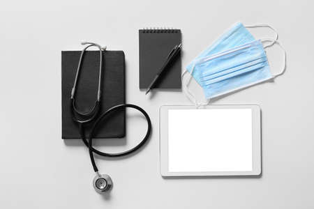 Composition with modern stethoscope and tablet computer on light backgroundの写真素材