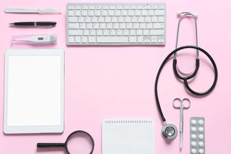 Frame made of modern stethoscope, tablet computer and keyboard on color backgroundの写真素材