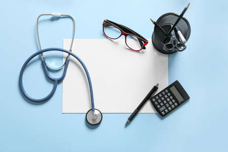 Composition with modern stethoscope, eyeglasses and sheet of paper on color backgroundの写真素材