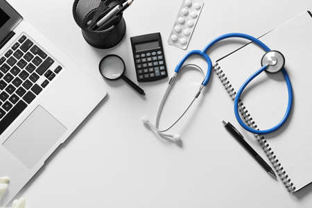 Composition with modern stethoscope and laptop on light background