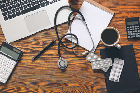 Composition with modern stethoscope and laptop on wooden background