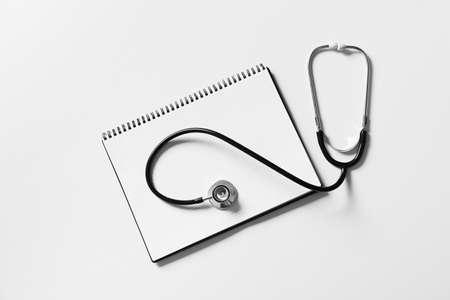 Modern stethoscope and notebook on light backgroundの写真素材