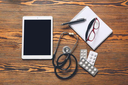 Composition with modern stethoscope and tablet computer on wooden backgroundの写真素材