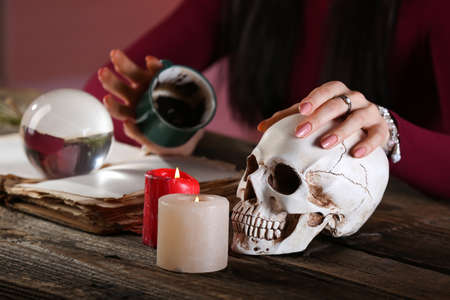 Fortune teller with human skull and spent coffee grounds reading future at tableの写真素材