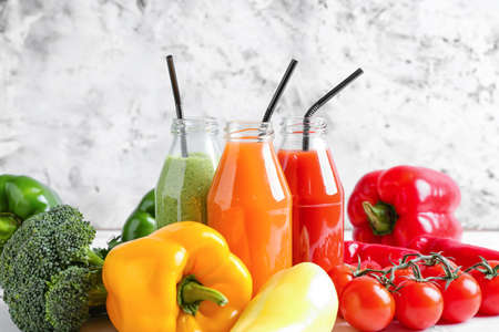 Bottles of healthy smoothie with different vegetables on light backgroundの写真素材