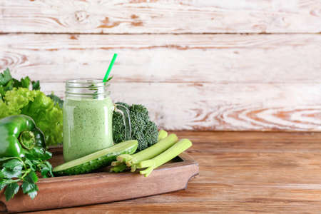 Mason jar of healthy smoothie with green vegetables on wooden backgroundの写真素材