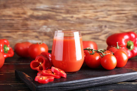 Glass of healthy smoothie with tomato and bell pepper on wooden backgroundの写真素材