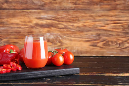 Glass of healthy smoothie with tomato and bell pepper on wooden backgroundの写真素材