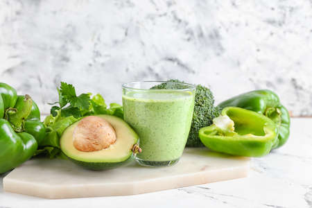 Glass of healthy smoothie with different vegetables on light backgroundの写真素材