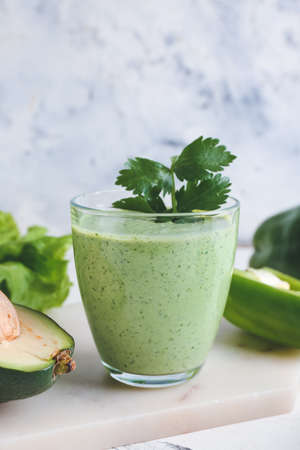 Glass of healthy smoothie with avocado and bell pepper on light backgroundの写真素材