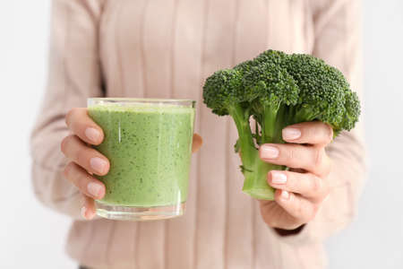Woman with glass of healthy broccoli smoothie on white background, closeupの写真素材
