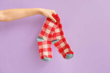 Hand with warm socks on color backgroundの写真素材