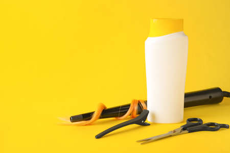 Bottle of shampoo and hairdresser's supplies on color backgroundの写真素材