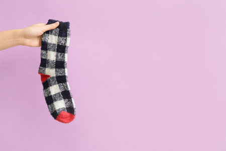Hand with warm sock on color backgroundの写真素材