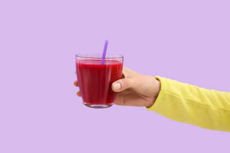 Hand with glass of healthy smoothie on color backgroundの写真素材