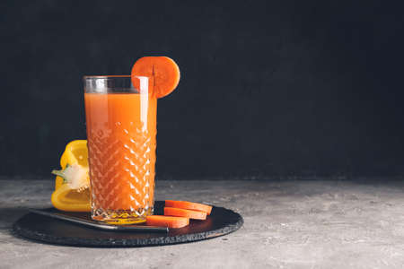 Glass of healthy smoothie with carrot and bell pepper on dark backgroundの写真素材