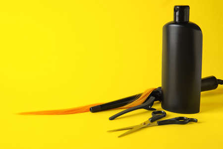 Bottle of shampoo and hairdresser's supplies on color backgroundの写真素材