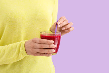 Woman with glass of healthy smoothie on color backgroundの写真素材