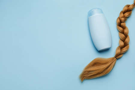 Bottle of shampoo and braided strand on color backgroundの写真素材