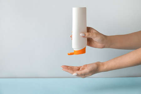 Woman with bottle of shampoo on light backgroundの写真素材