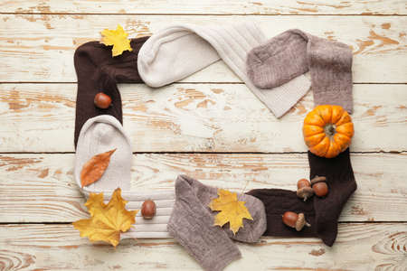 Frame made of warm socks and autumn leaves on wooden backgroundの写真素材