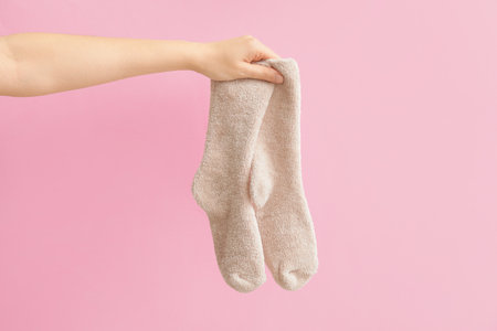 Hand with warm socks on color backgroundの写真素材