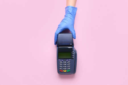 Female hand with payment terminal on color backgroundの写真素材