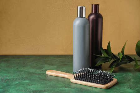 Bottles of shampoo and hair brush on color backgroundの写真素材