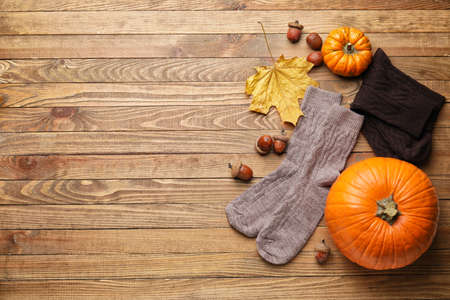 Warm socks, autumn leaves and pumpkins on wooden backgroundの写真素材
