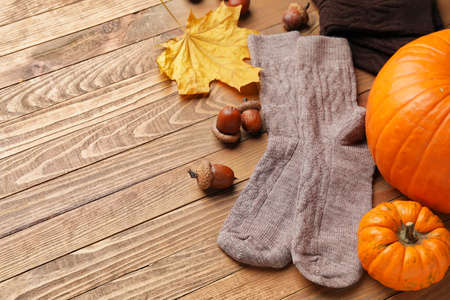 Warm socks, autumn leaves and pumpkins on wooden backgroundの写真素材