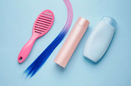 Bottles of shampoo, hair strand and brush on color backgroundの写真素材