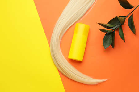 Bottle of shampoo and hair strand on color backgroundの写真素材