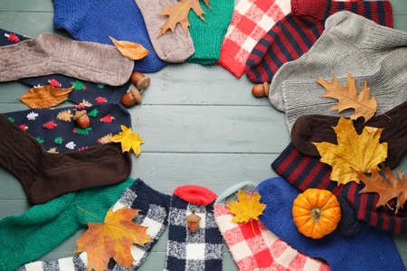 Frame made of warm socks, autumn leaves and pumpkin on wooden backgroundの写真素材